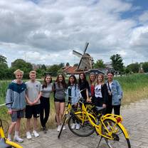 students with bikes in front of a windmill