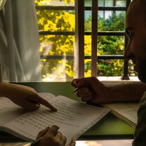 Two Omeida students studying together Two students bent over textbooks studying