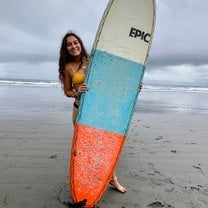 Me holding a surfboard at Jacó beach, Costa Rica where I took surf lessons through USAC