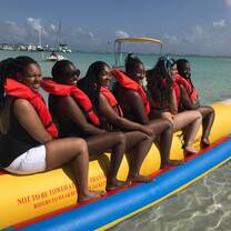 Six students are on a raft and are smiling back at the camera