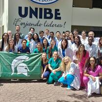A group photo in front of a hosptial in the dominican republic with a michigan state university flag in front of the students