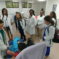 A group of students in their scrubs, observing as a physcician accesses a child