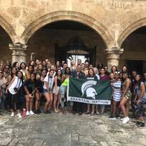 A large group photo in front of a culturally relevant building