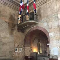 An old, culturally signiifcant building with 4 dominican republic flags in stands on the balcony in the corner