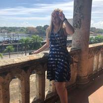 A female standing on an ancient balcony, smiling at the camera