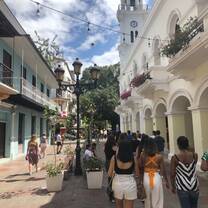 An alley with students walking down the cobble side-walk, the sun and blue skies ahead of them