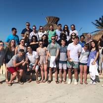 A group photo of participants in front of a hut on the sunny beach