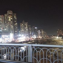 It is a city outside of Seoul; a view from a walking bridge looking over at colorful skyscrapers. 