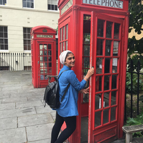 A student posing by one of London's famous red telephone boxes