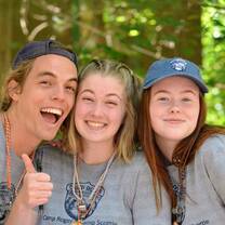 Image of 3 young adults smiling together in the woods