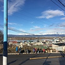 Line of people walking with city and mountain in background, big blue sky above