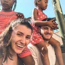 Duas crianças sentadas nos pescoços de dois voluntários.