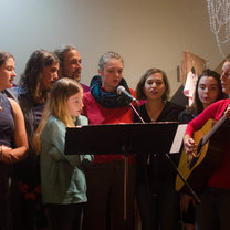 Participant clustered around a microphone and performing as backup singers for a local artist