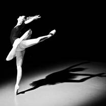 Black and white photo of a ballerina with her leg in attitude position.