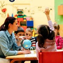Passionate about teaching Teacher sitting at table teaching young kids