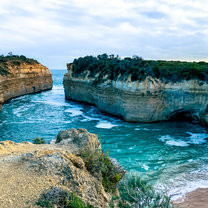 Cliffs sectioning off vibrant blue water and a smooth beach from the open ocean.