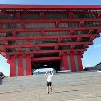 Outside the Shanghai Art Museum, a gigantic building made out of red wooden slabs interlocking in a traditional Chinese style.