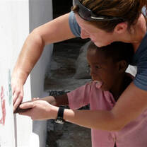 Volunteer and child painting on walls