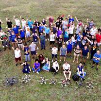 Students stand in a field with the drones they have just built and flown.