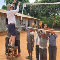 Greg putting up the volleyball net with the help of eager students.