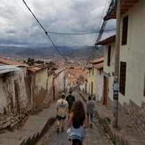 Students walk a street with old buildings and mountains in the background.