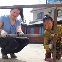 A participant and Nepalese girl work together to prepare for painting