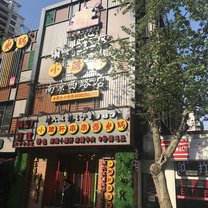 A colorful front of a restaurant that has neon Chinese characters all over it