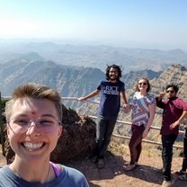 A group of friends smiles in front of the cliffs of Mahabaleshwar.