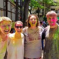 A group of friends smiles, covered in colored powder, after playing Holi with local schoolchildren in Pune.