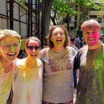 A group of friends smiles, covered in colored powder, after playing Holi with local schoolchildren in Pune.