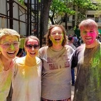 A group of friends smiles, covered in colored powder, after playing Holi with local schoolchildren in Pune.