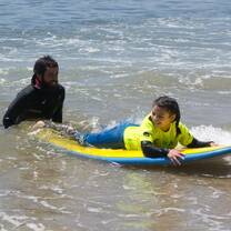 Interns and staff members help students improve their surfing abilities.