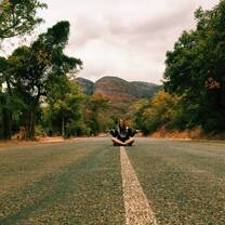 Student sitting in the middle of an empty road