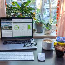 A desk with a laptop, glasses, and coffee