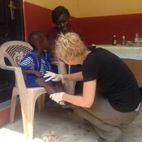 Public Health intern in Ghana treating a child for a minor wound