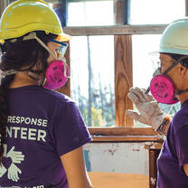 Volunteers in respirators examine a window frame