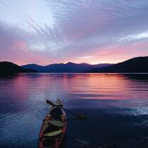 A sea kayak rests along the shore at sunset on a NOLS New Zealand expedition.