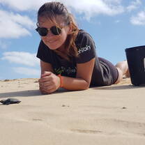 Sea turtle hatchling and volunteer on the beach