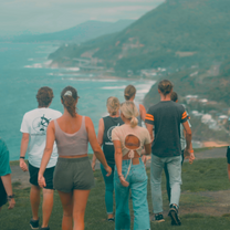 A group of people walking towards a backdrop of the Ocean and mountains