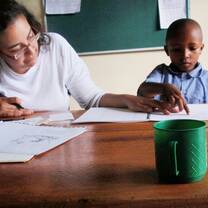 Volunteer in Tanzania helping a student with a reading assessment 