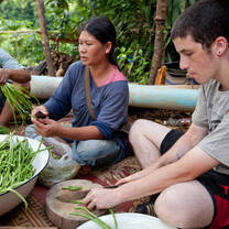 Student sitting with a Laotian and preparing a meal