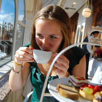 Student drinking tea with a tower of pastries in front of her 