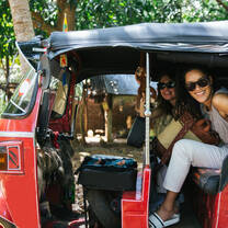 Two volunteers riding in a red tuk tuk in Tanzania 