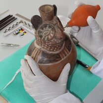 Cleaning a Moche ceramic vessel