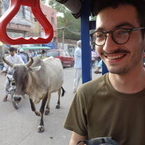 traveller in a tuk tuk with a goat behind