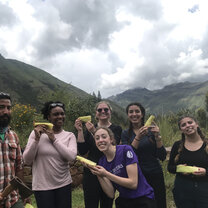 Enjoying toasty humitas in Pisac, Peru group holding corn humitas in Peru