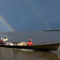 A small boat on the Amazon river under a rainbow