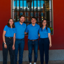 The RVF International team standing together, smiling and wearing blue uniforms in front of a red building, ready to support participants in their Teach English in Spain program and cultural exchange experience.
