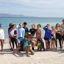 Projects Abroad Diving Conservation Team poses in front of crystal blue ocean survey site