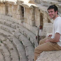 A student sits in the top row of the Amman citadel, smiling at the camera.